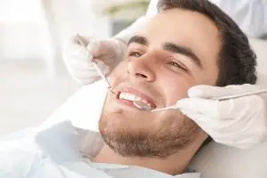 Dentist,Examining,Teeth,Of,Young,Man,In,Clinic